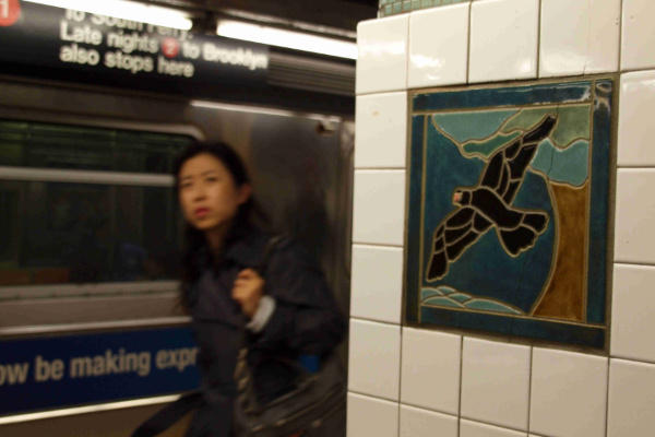 Mädchen vor einem Mosaik mit Vogel in der Subway von New York